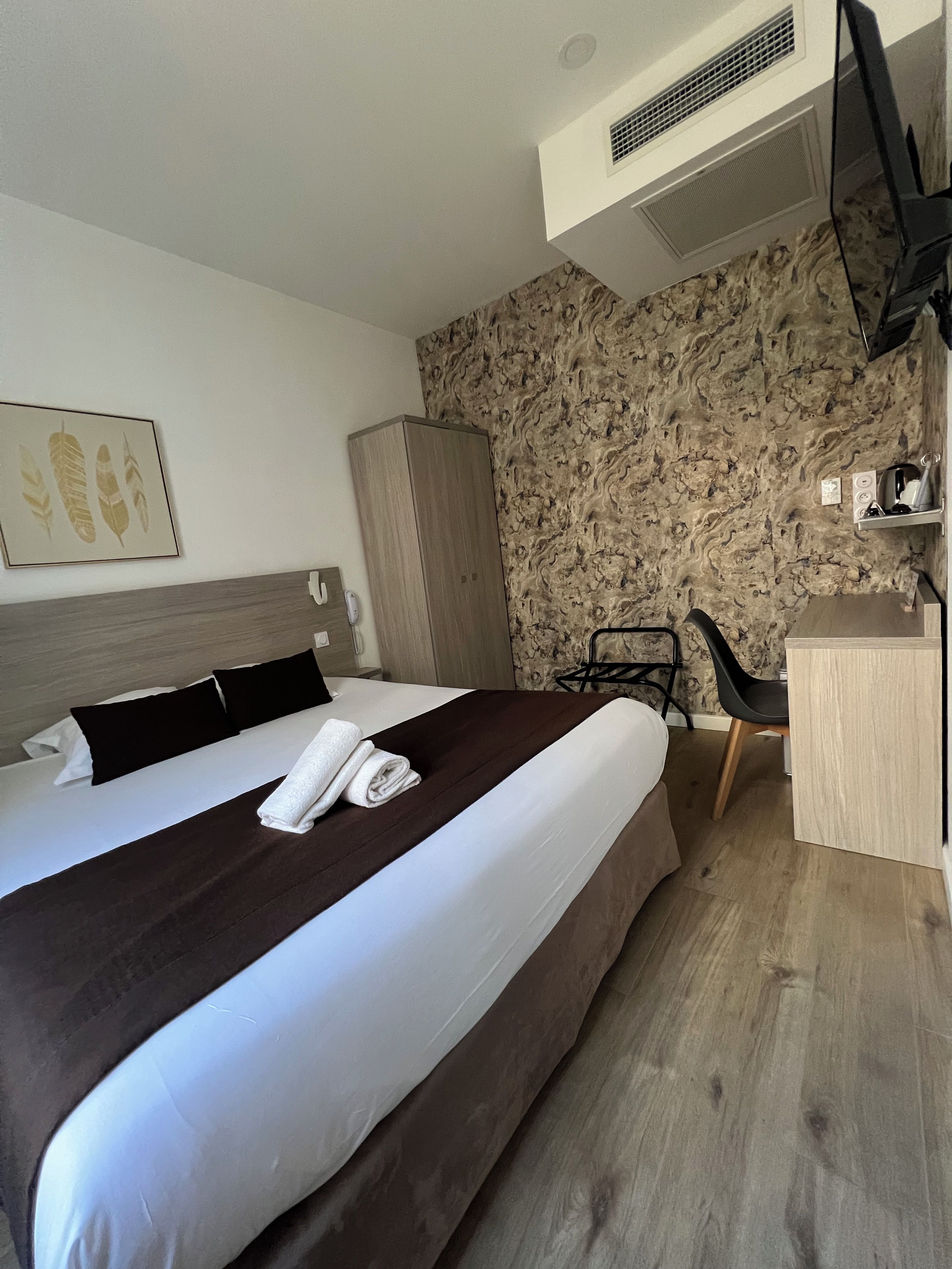 Ein Hotelzimmer mit Bett, Schreibtisch und Kleiderschrank.