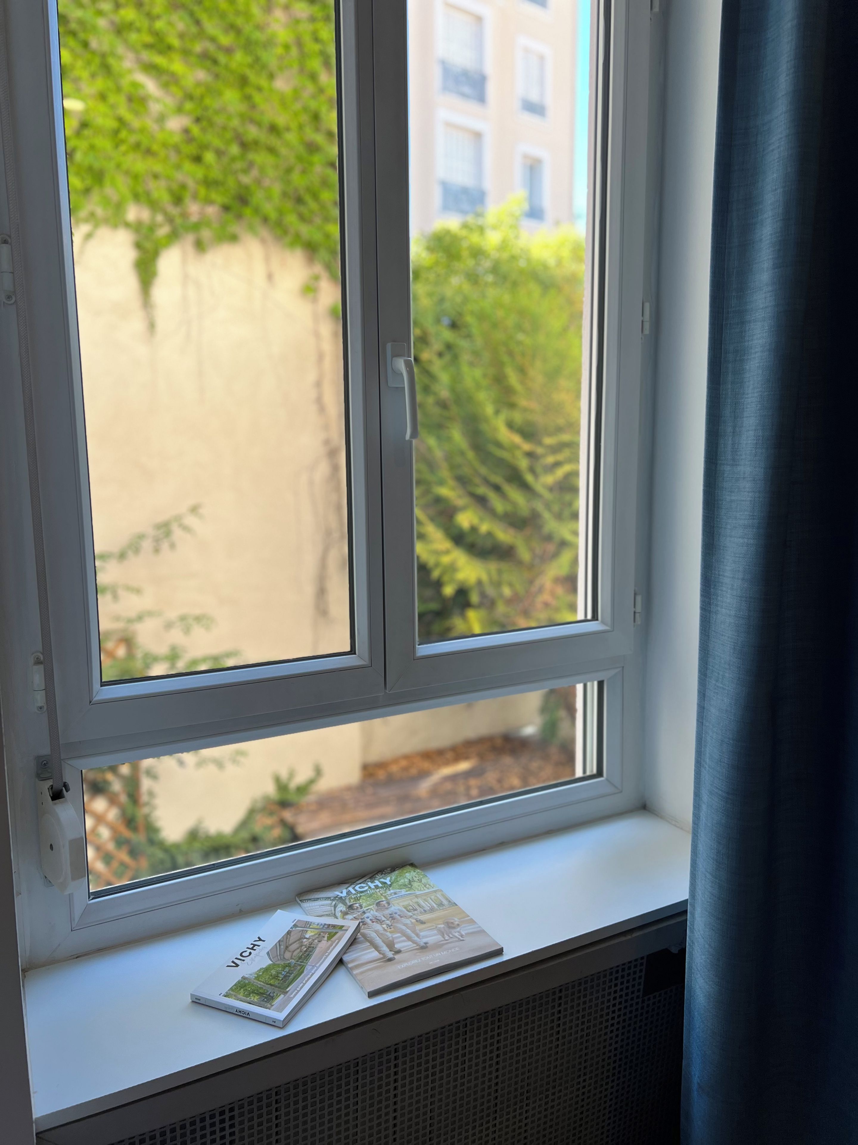 Una ventana con vistas a zonas verdes y un edificio.