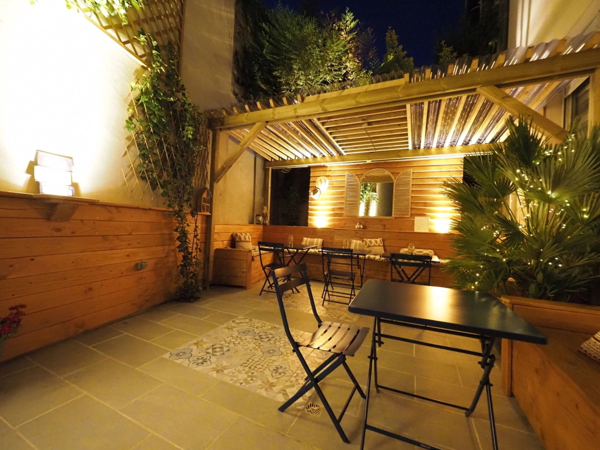Une terrasse extérieure avec un sol en bois, une table et des chaises.
