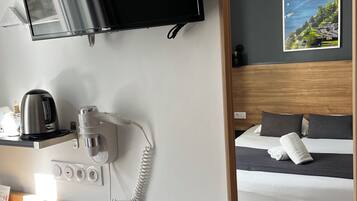 Hotelkamer met een bed, een flatscreen televisie aan de muur, een koffiezetapparaat, een telefoon en een landschapschilderij.