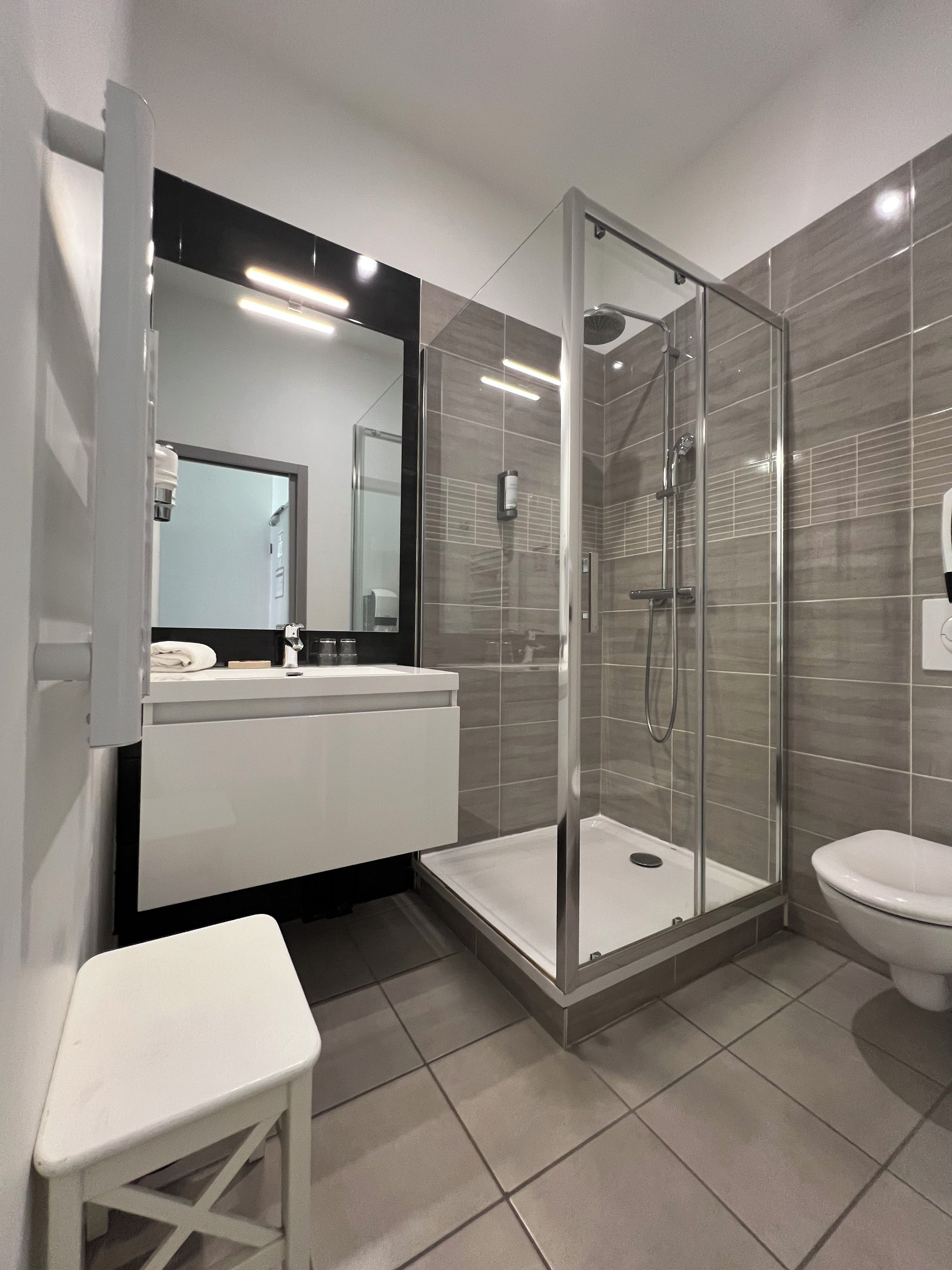 Een moderne badkamer met een douchecabine van glas, een witte wastafel en een toilet.