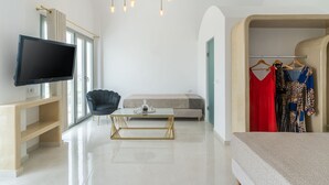 A modern room with a flat-screen TV, a sofa, a coffee table, and a wardrobe with clothes. - Golden Star (Santorini)