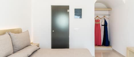 A bedroom with a bed, a wardrobe, and a door leading to a hallway.