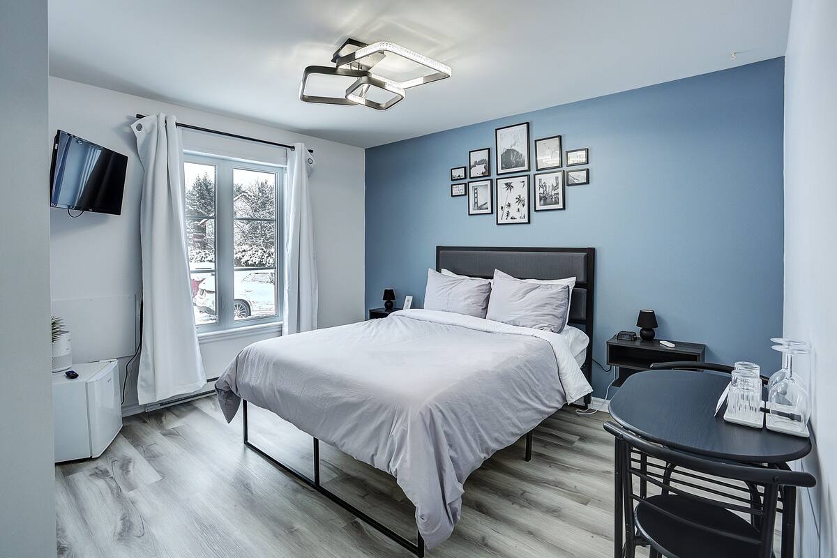 A bedroom with a bed, bedside tables, a TV, and a window with curtains.