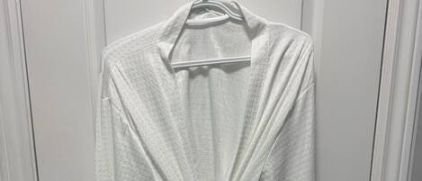 A white robe hanging on a door with a black hanger.