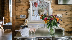 A wooden wall with a mirror, a vase of flowers, a champagne bottle, and two glasses on a table. - Lymestone Boutique Accommodation (Grange-over-Sands)