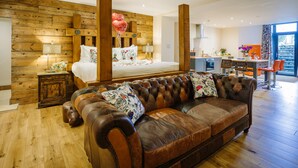 A modern bedroom with a large bed, a leather sofa, and a wooden wall. - Lymestone Boutique Accommodation (Grange-over-Sands)
