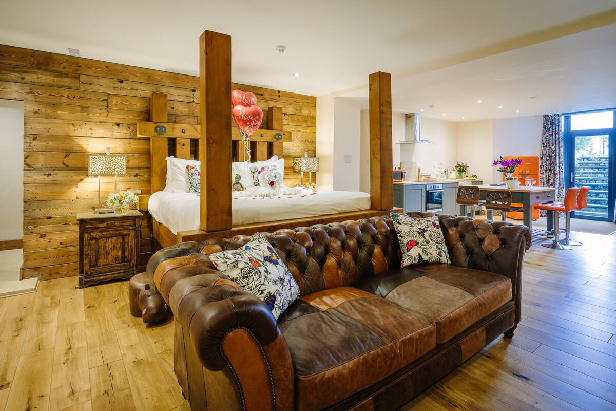 Une chambre à coucher moderne avec un grand lit, un canapé en cuir et un mur en bois.