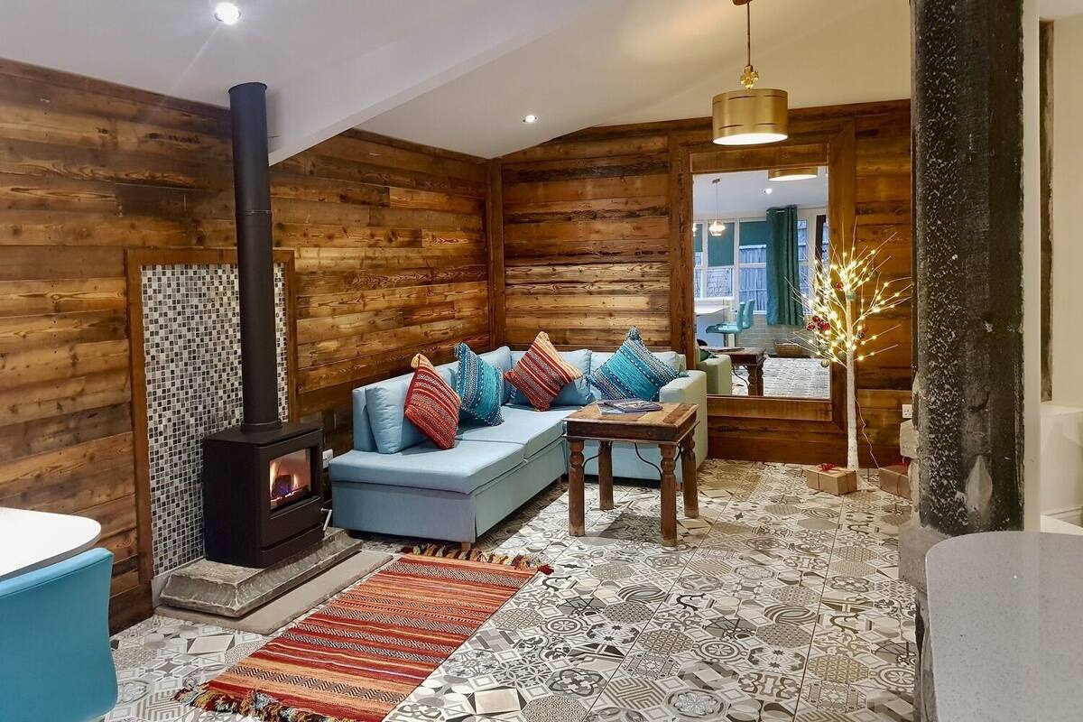 L’intérieur chaleureux d’un chalet en bois comprend un canapé, une petite table, une cheminée et un arbre décoratif.