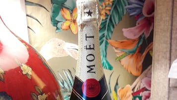 Una botella de Moët & Chandon, dos copas con adornos rojos y un jarrón decorativo sobre una mesa de madera.
