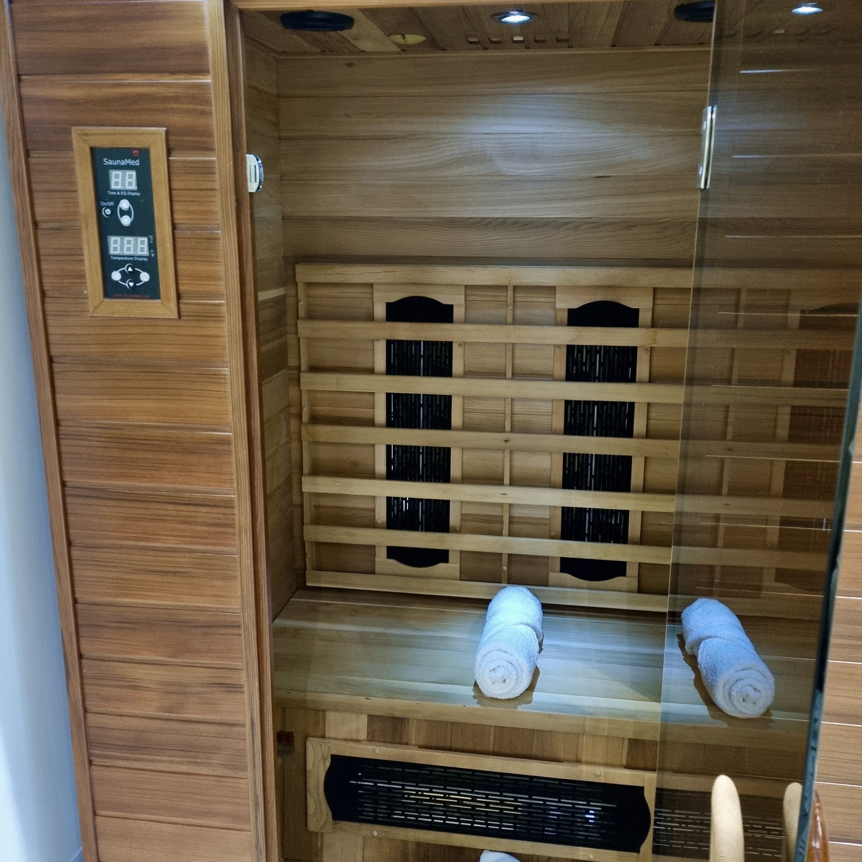 A sauna with wooden shelves and a control panel.