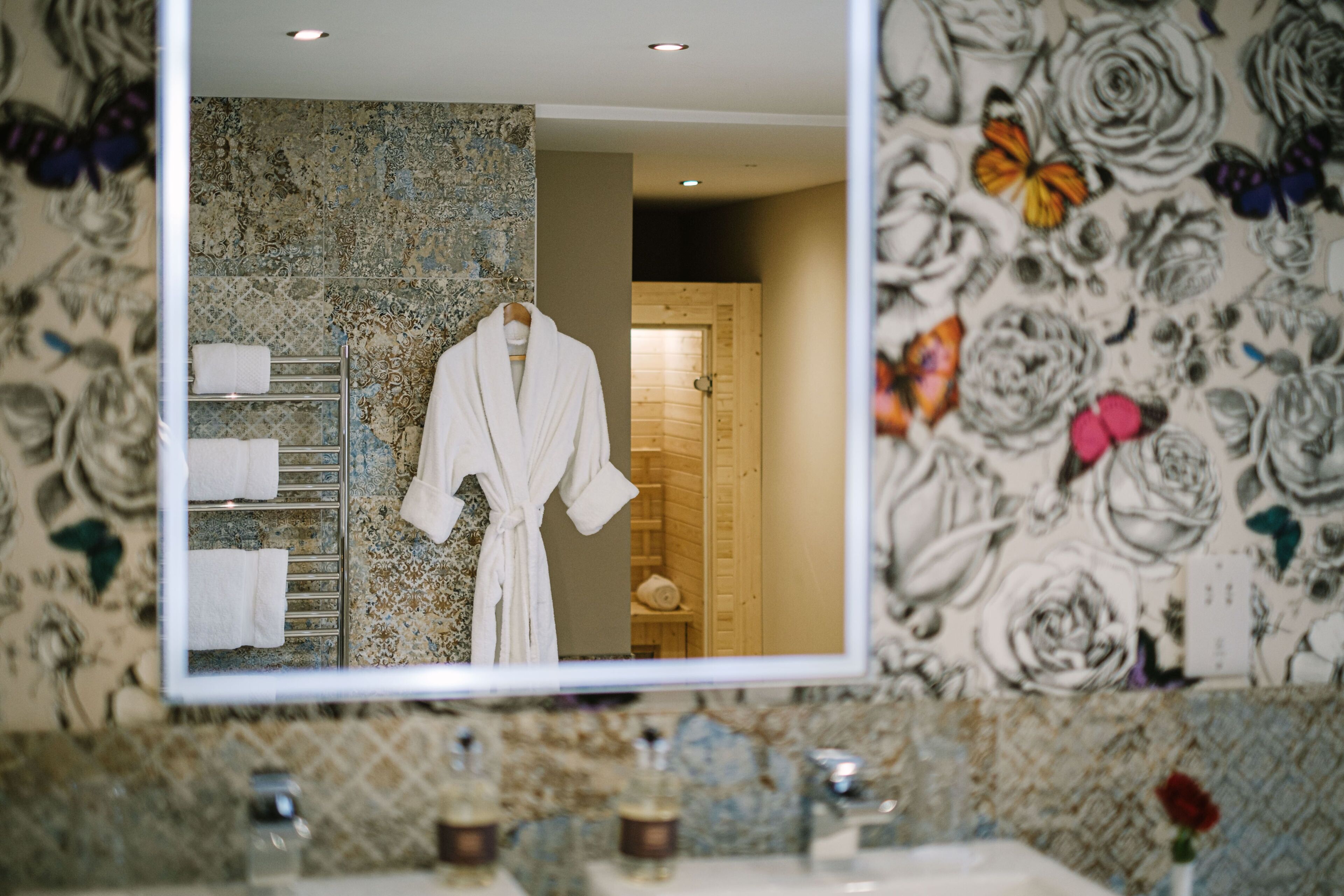 Une salle de bain avec un grand miroir, un porte-serviettes et une porte en bois.