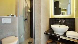 A modern bathroom with a glass-enclosed shower, a white sink, and a toilet. - Hotel Auguste (Paris)