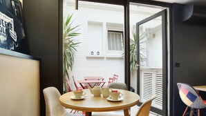A dining area with a round table, chairs, and a view of the outside through a glass door. - Hotel Auguste (Paris)