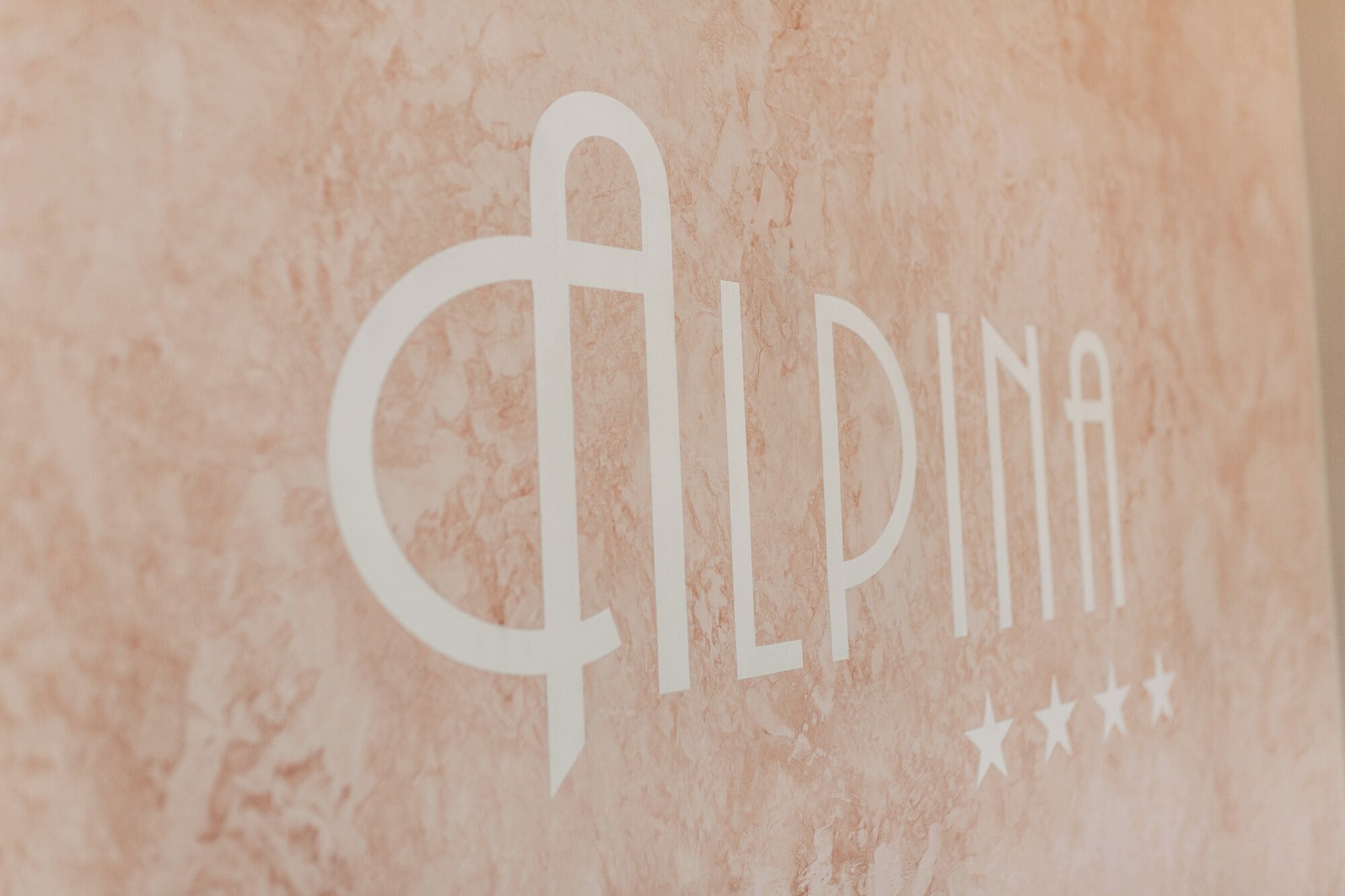 Un logo comportant le texte « ALPINA » et trois étoiles en dessous.