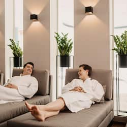 Relax in a serene space with a large sofa, floor lamps, and lush greenery.
