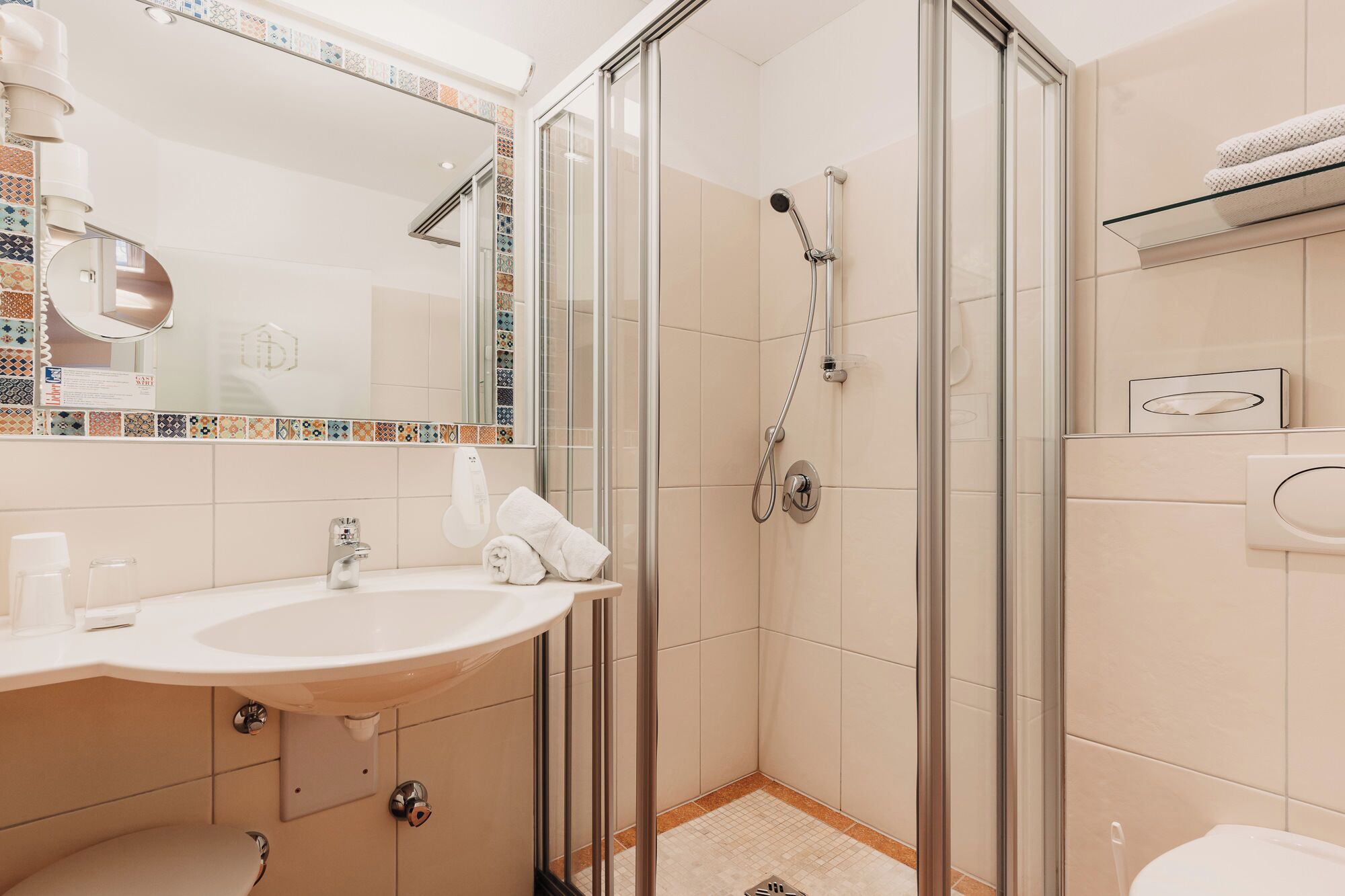 A modern bathroom with a glass-enclosed shower, a sink with a mirror, and a towel rack.