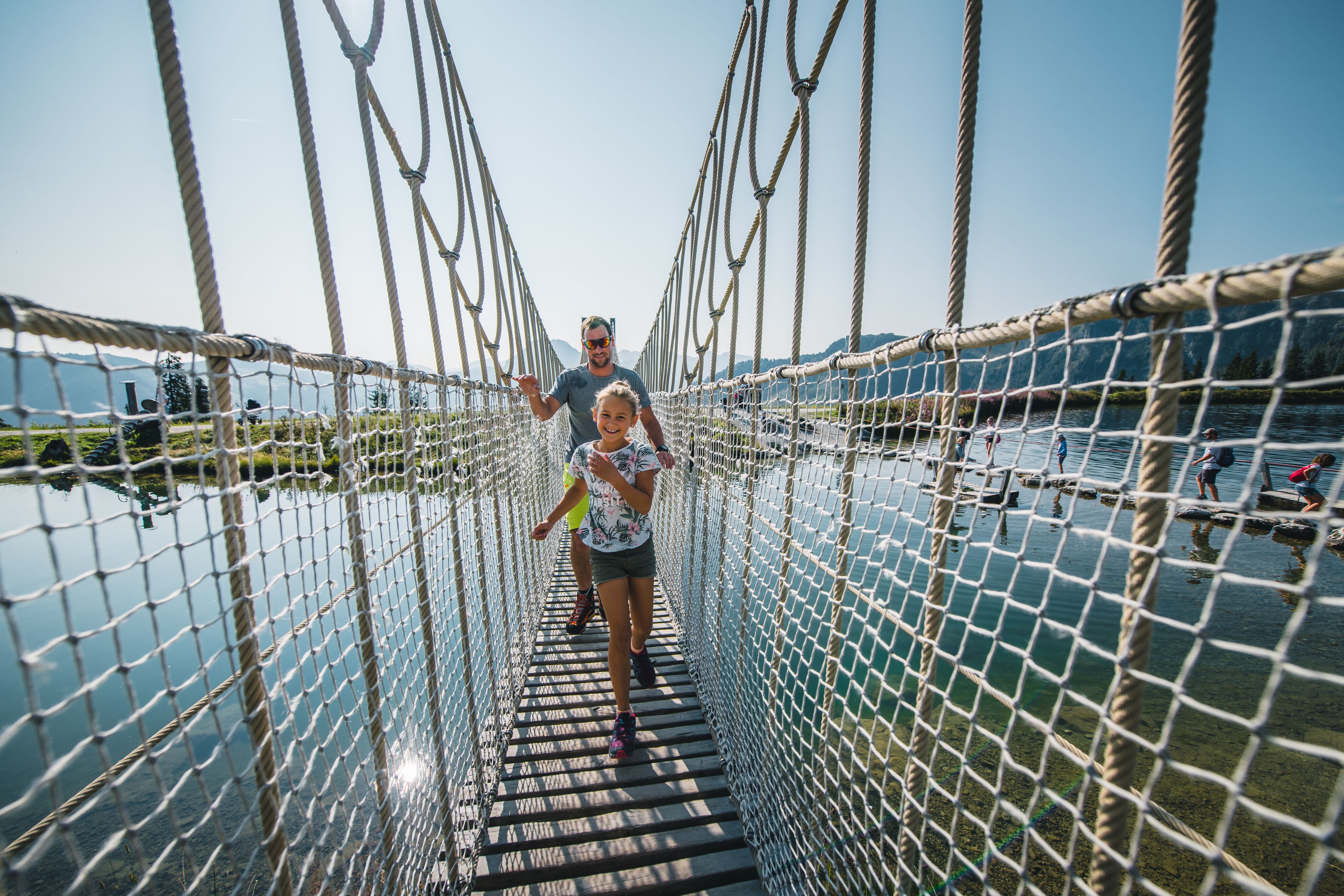A rope bridge over water with people walking on it.