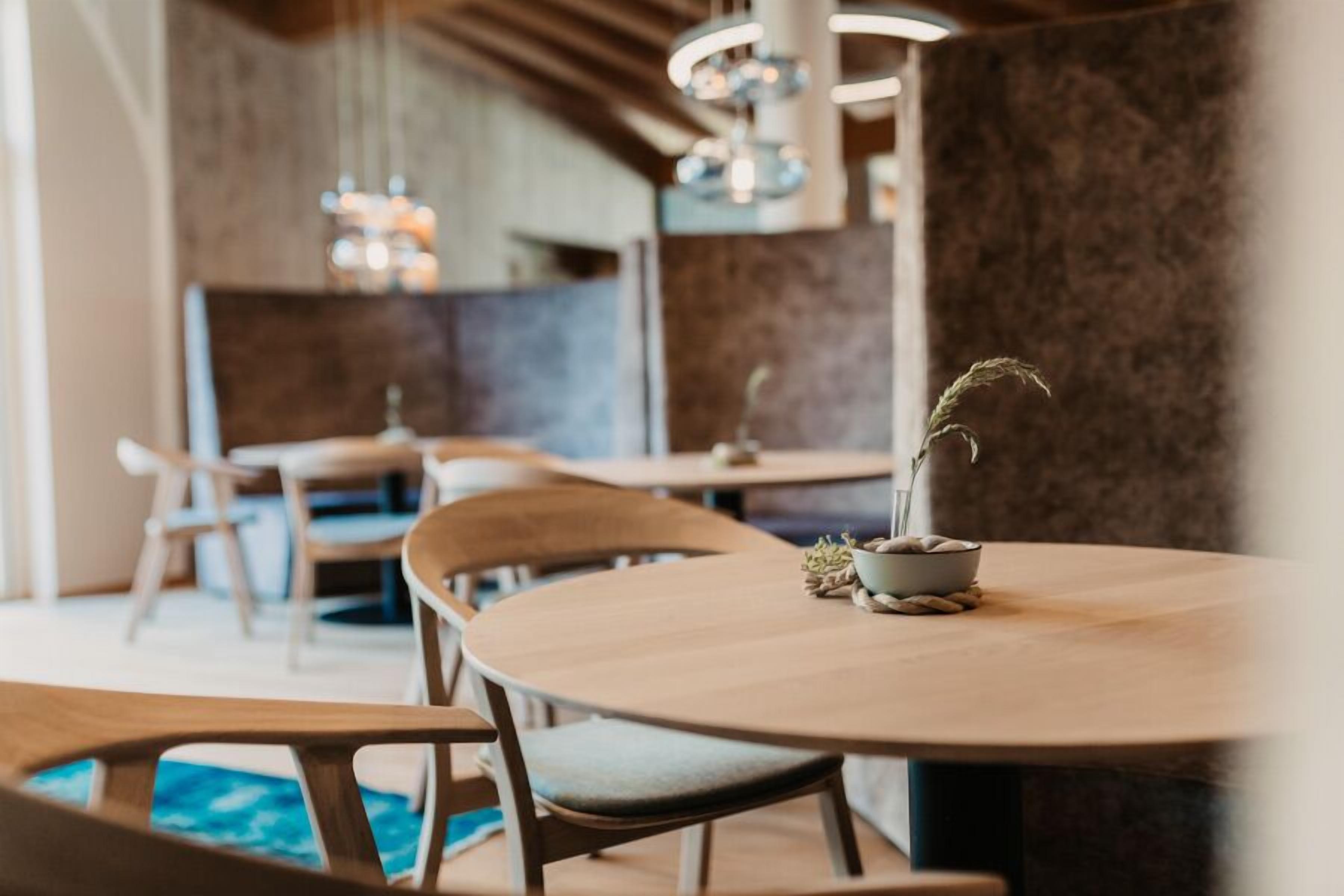A cozy dining area with round tables and wooden chairs, featuring a small potted plant on one table.