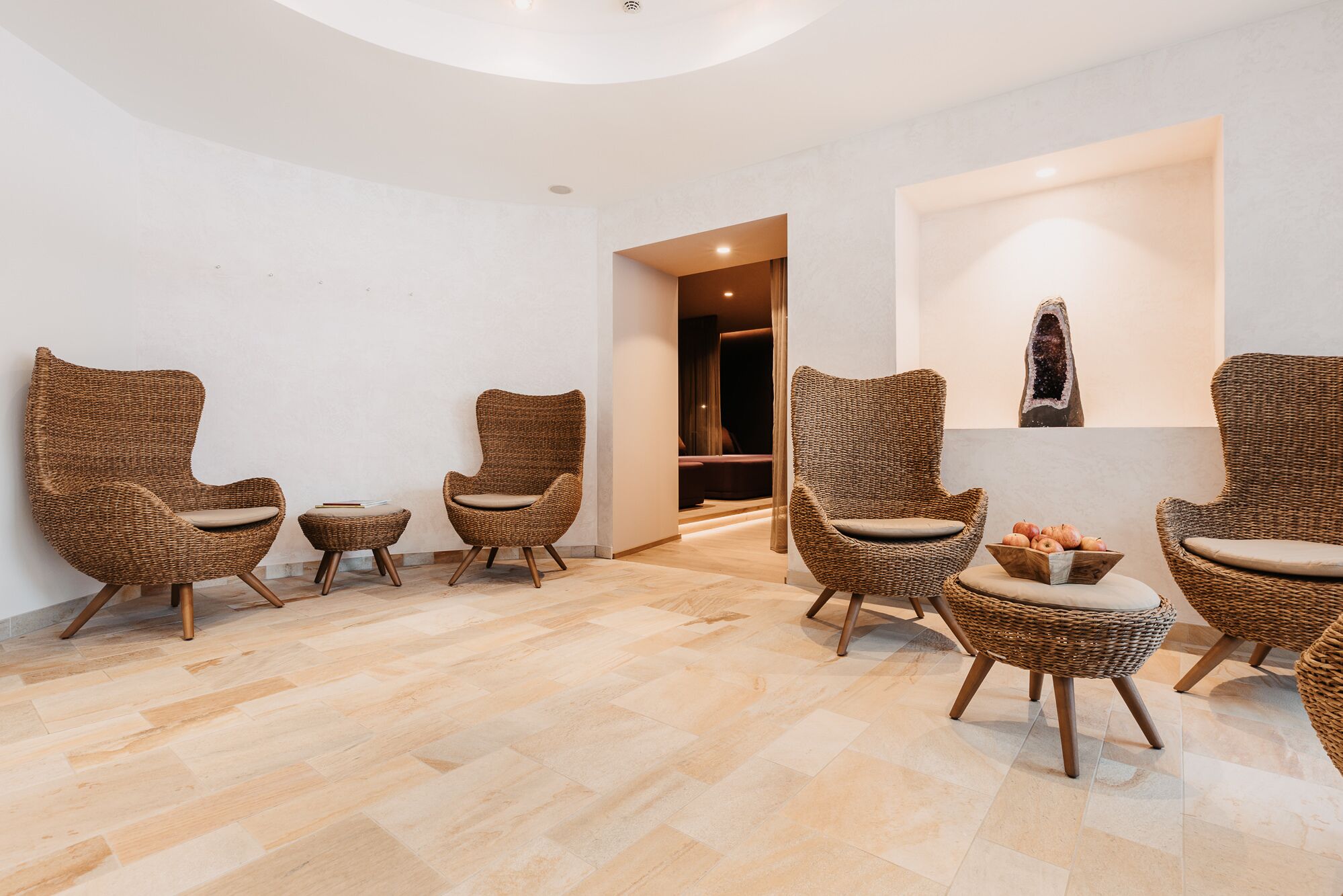 A room with wicker chairs, a small table, and a wall-mounted sculpture.