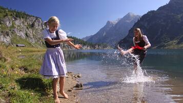 Dos personas juegan en un lago con montañas al fondo.