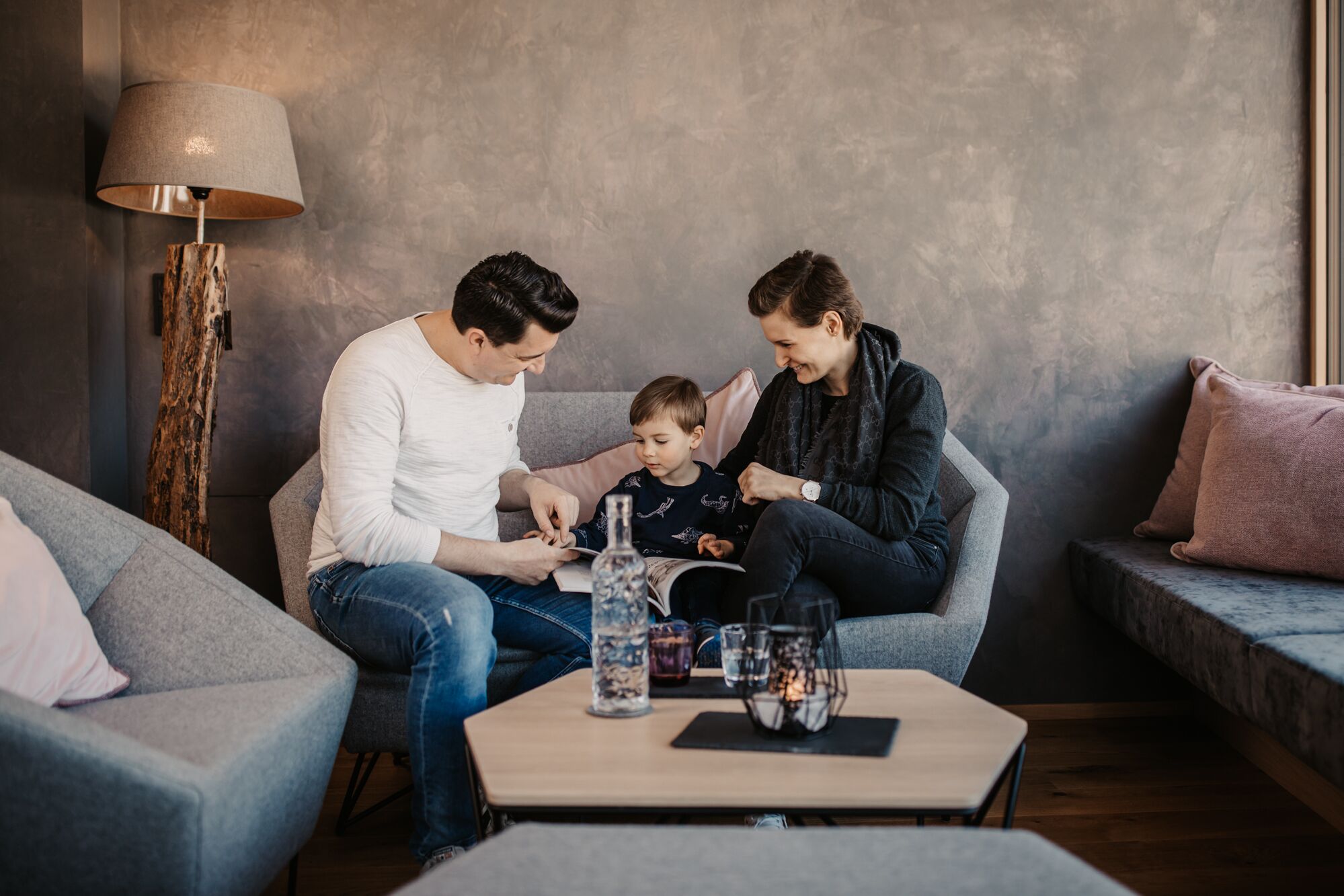 Ein Wohnzimmer mit einer Couch, einem Couchtisch mit Getränken und einer Lampe.