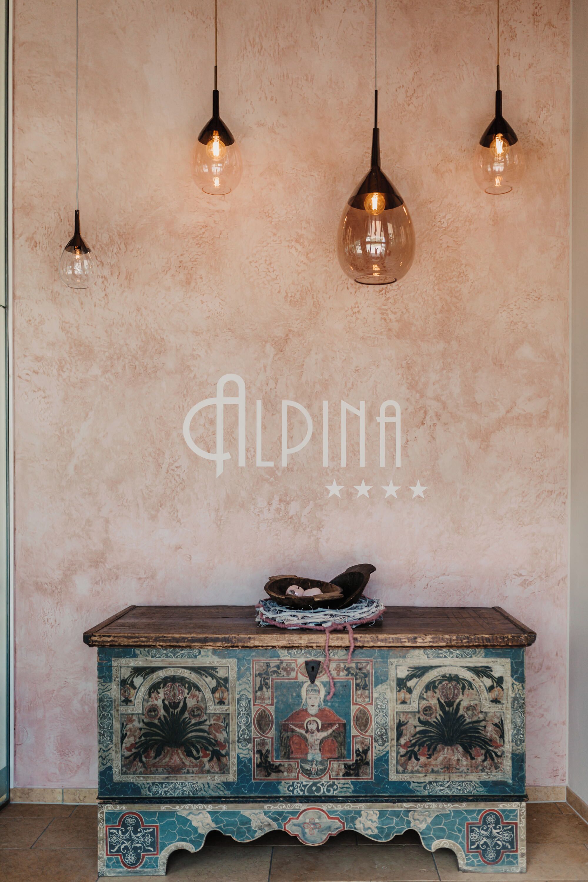 A room with a textured wall, a decorative chest, and pendant lighting.