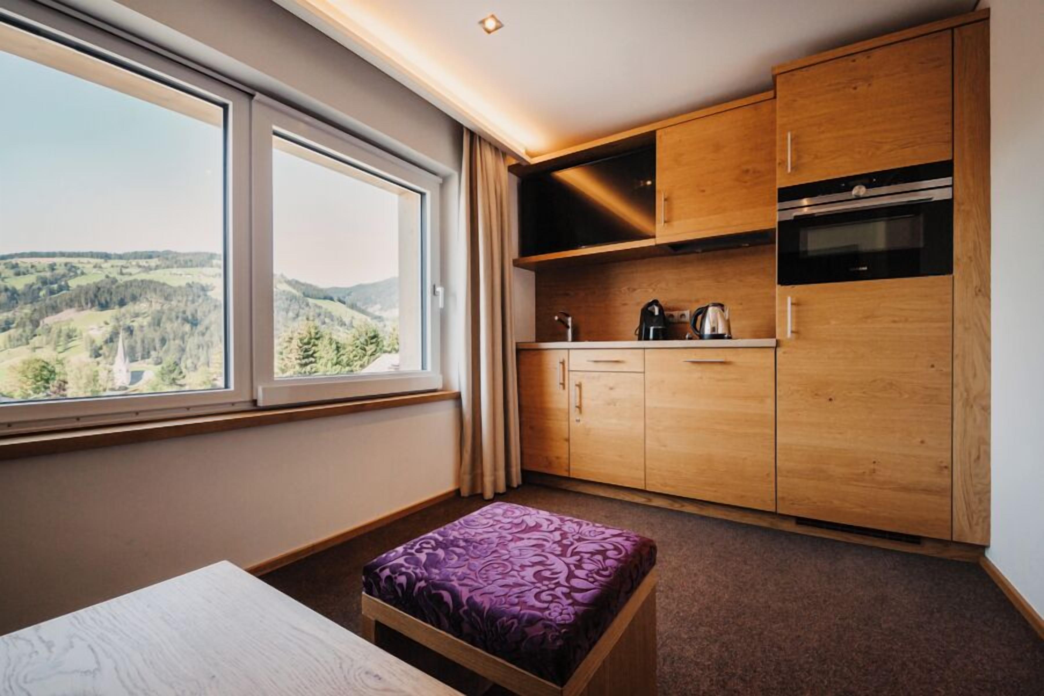 Una cocina compacta con armarios de madera, horno integrado y ventana con vistas a un paisaje pintoresco.