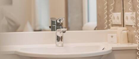 A modern bathroom with a white sink, a mirror, and a towel rack.