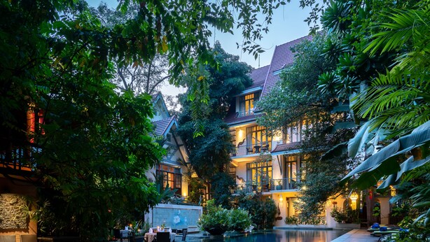 A luxurious hotel with a large indoor pool, lush greenery, and elegant architecture.
