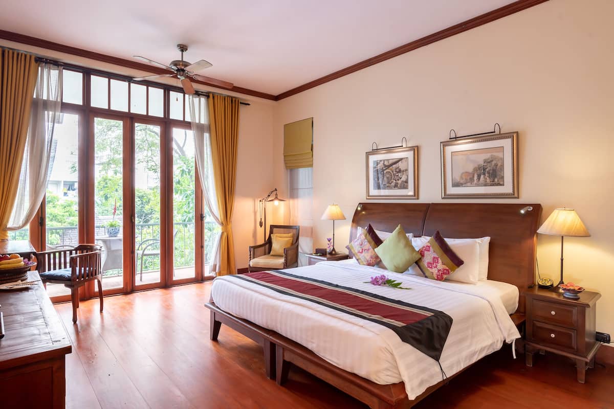 A spacious bedroom with a large bed, wooden headboard, and two bedside tables with lamps.