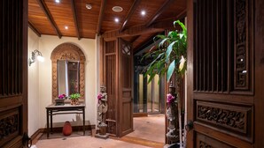 A hallway with wooden paneling, a marble floor, a statue, a potted plant, and a large vase.