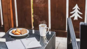 Una mesa con un plato de pasteles, una taza de café, un cuaderno y un bolígrafo.
