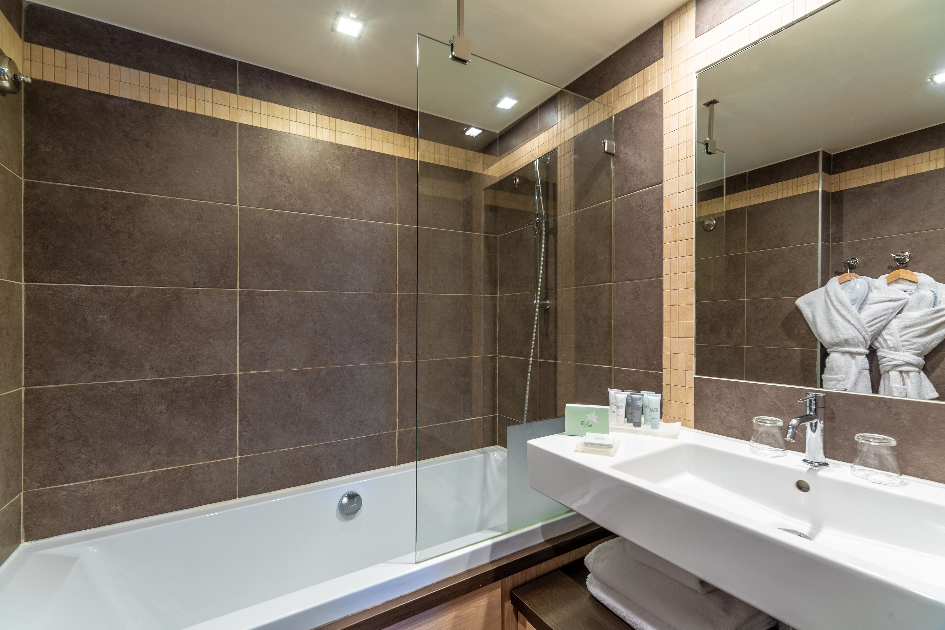 A modern bathroom with a glass-enclosed shower, a white sink with a mirror, and a towel rack.