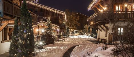Un sendero cubierto de nieve que conduce a un edificio de madera con luces navideñas.