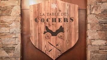 A wooden sign with the text "LA TABLE DES COCHERS" and a horse-drawn carriage illustration.