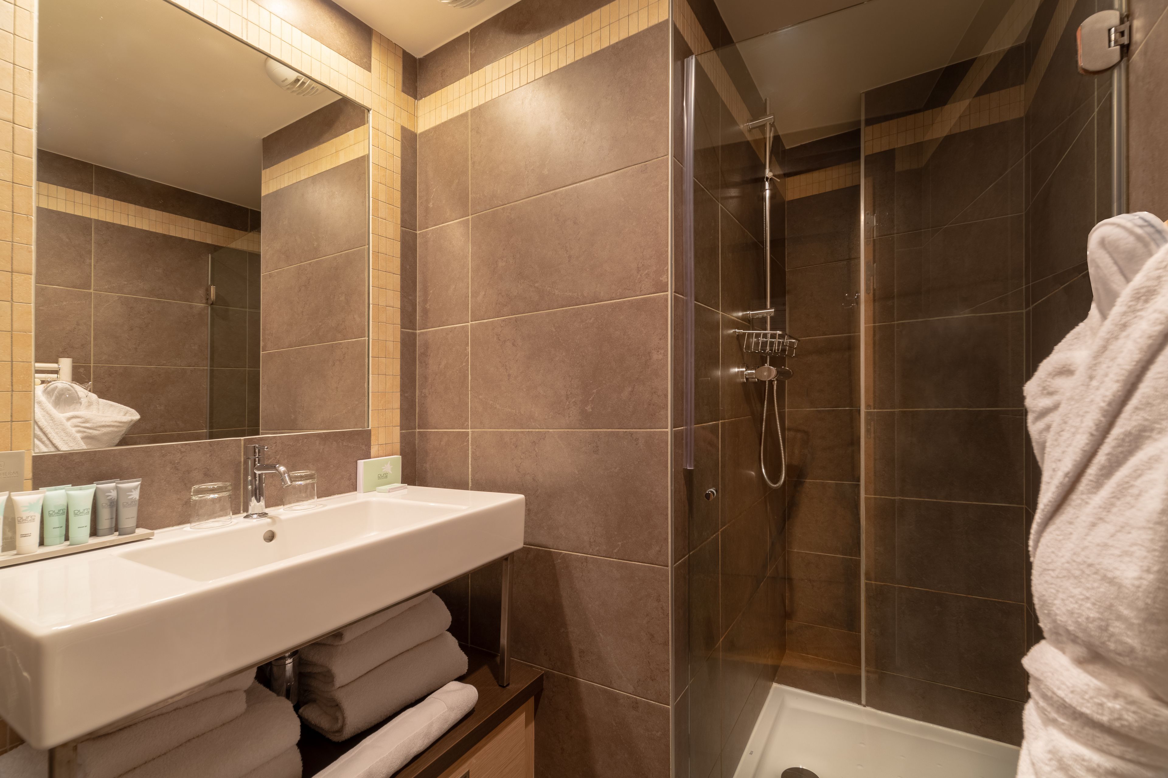 A modern bathroom with a large sink, a glass shower enclosure, and a mirror.