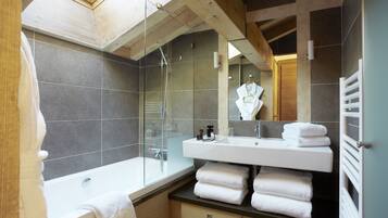 Une salle de bain moderne avec un puits de lumière, une douche en verre, un lavabo blanc et un porte-serviettes.