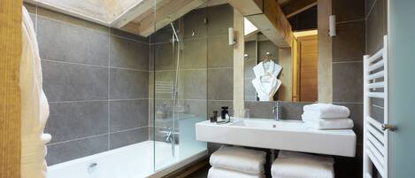 Un baño moderno con tragaluz, cabina de ducha de cristal, lavamanos blanco y toallero.