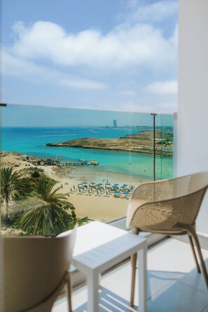 Un balcón con vista a una playa, un muelle y un edificio lejano.