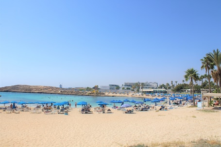 En la playa, sillas reclinables de playa, sombrillas, toallas de playa