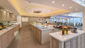 A modern breakfast buffet with multiple food stations, a central serving area, and a seating area with tables and chairs. - Tasia Maris Sands - Adults Only (Ayia Napa)