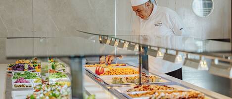 A buffet with various food items and a chef in the background.