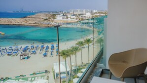 A beach view from a balcony with beach umbrellas, lounge chairs, and a clear blue sea. - Tasia Maris Sands - Adults Only (Ayia Napa)