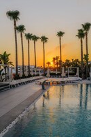 Una piscina al aire libre, sombrillas, sillones reclinables de piscina