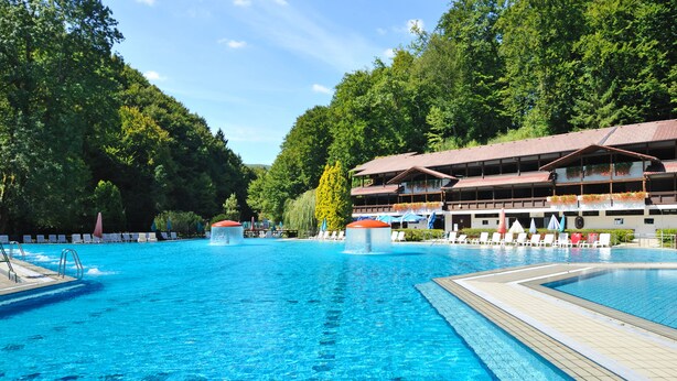 A swimming pool with lounge chairs and a building with a red roof. - Hotel Šmarjeta - Terme Krka (Smarjeske Toplice)