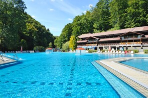 A swimming pool with lounge chairs and a building with a red roof. - Hotel Šmarjeta - Terme Krka (Smarjeske Toplice)