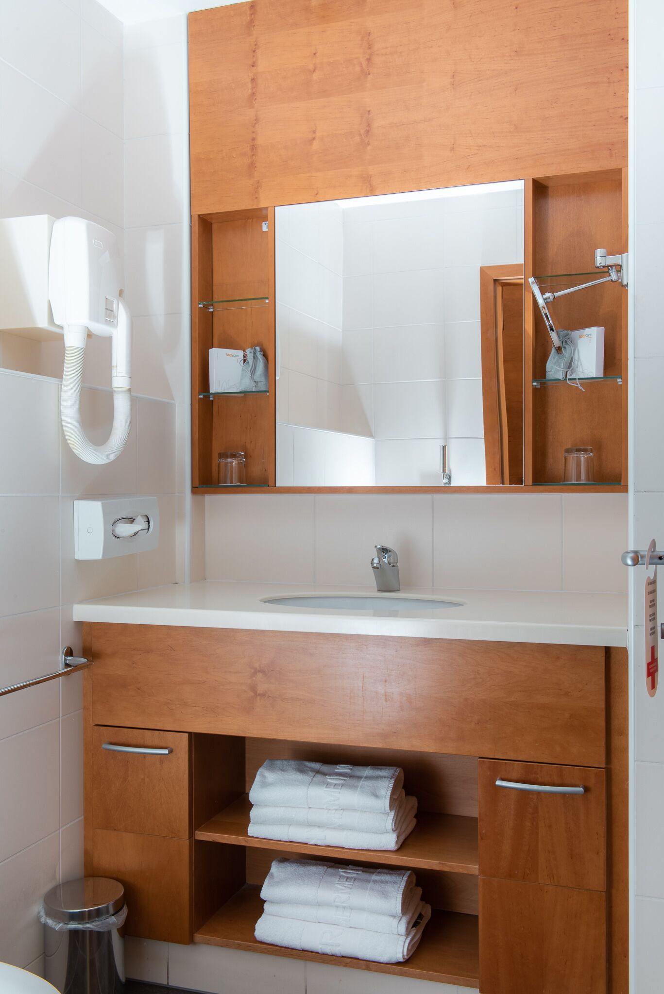 Un baño moderno con tocador de madera, un espejo, un lavabo y un perchero para toallas.