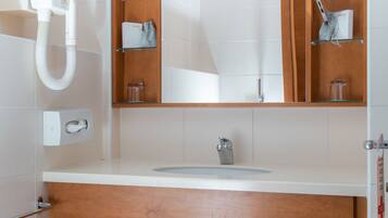Un baño moderno con tocador de madera, un espejo, un lavabo y un perchero para toallas.