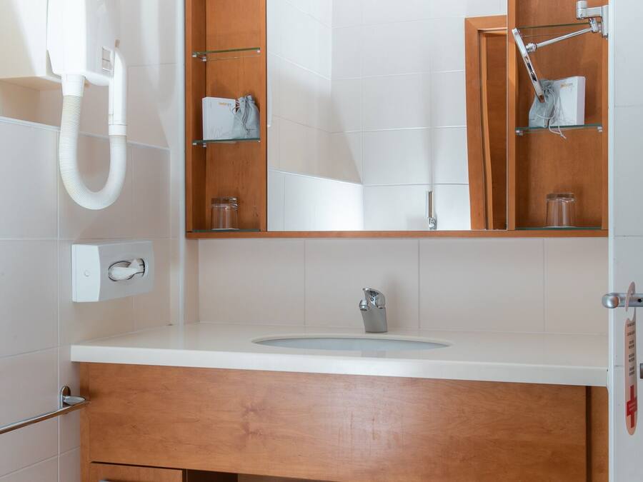 Un baño moderno con tocador de madera, un espejo, un lavabo y un perchero para toallas.